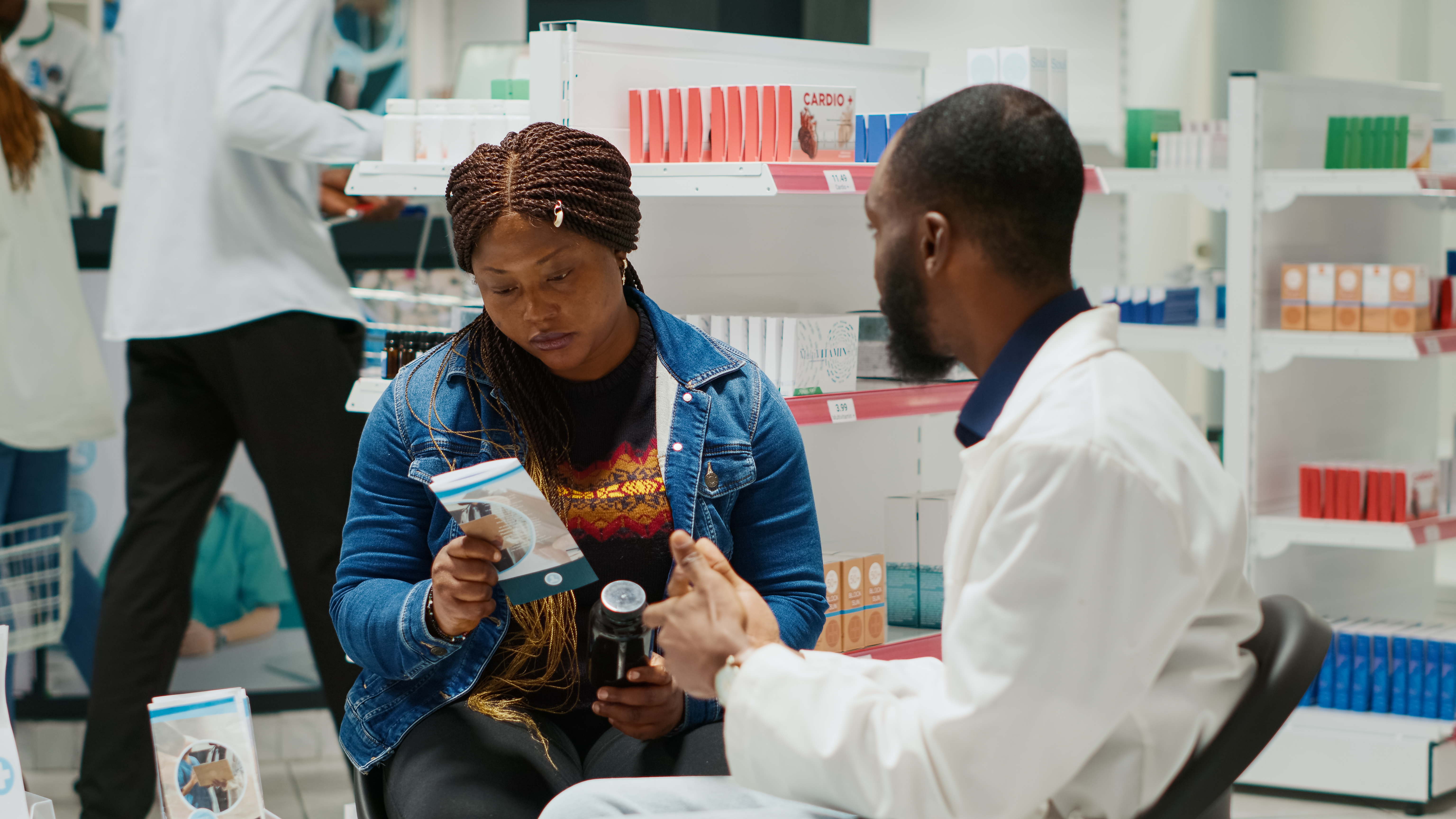 Drugstore employee recommending medicine to client, talking about prescription treatment with vitamins of drugs. Man explaining disease medicaments and supplements in pharmacy.
